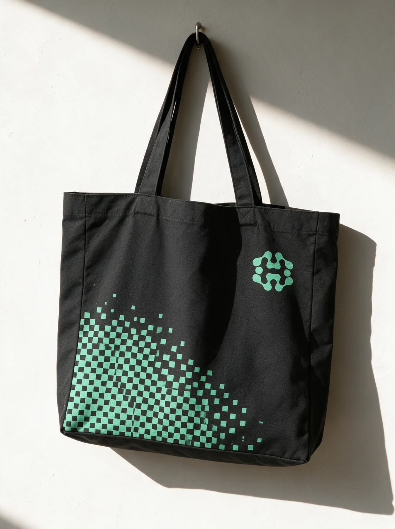 A charcoal canvas tote with a mint pixel pattern and House emblem.